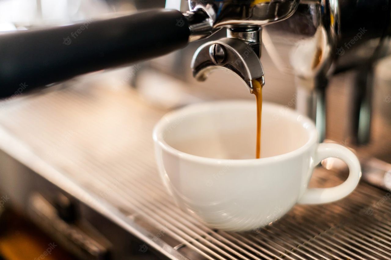 In the photo, a white cup in a coffee machine, which makes espresso - Metrópoles